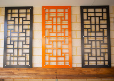 Decorative aluminium panels mounted on a brick wall featuring custom metal fabrication designs