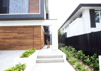 Man standing outside a large house with custom sheet metal fabrication fences in Perth
