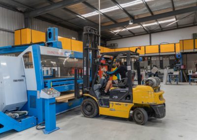 An employee operating forklift carrying aluminium sheets in a fabrication machine